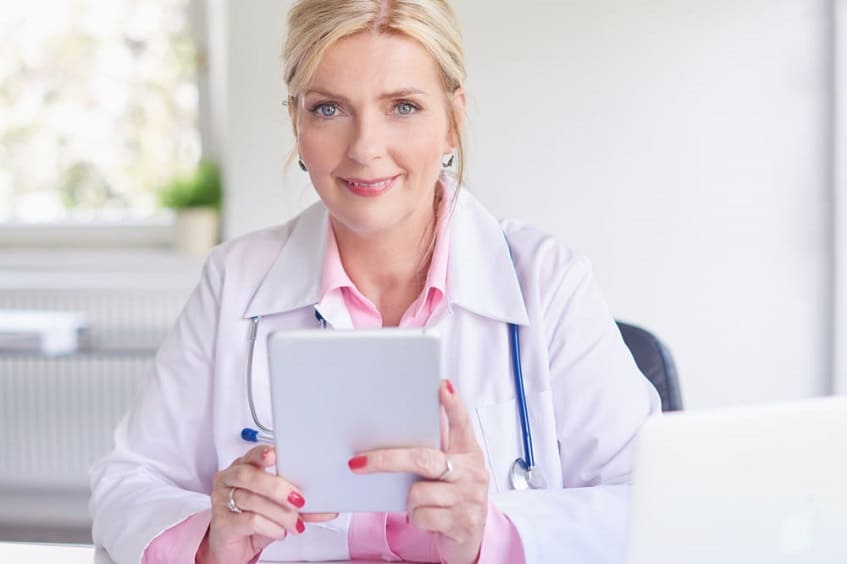Женщина врач держит в руках планшет